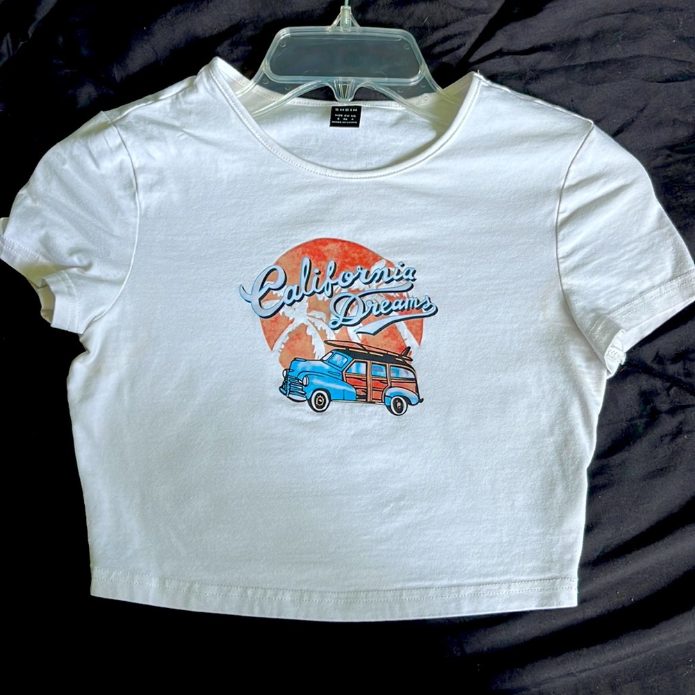 this top is from shein, it is a white shirt with blue, black, and tan-orange top